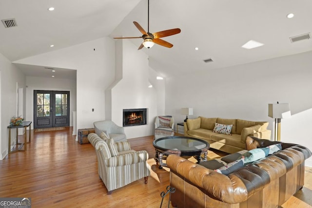 living room with ceiling fan, light hardwood / wood-style flooring, high vaulted ceiling, and french doors