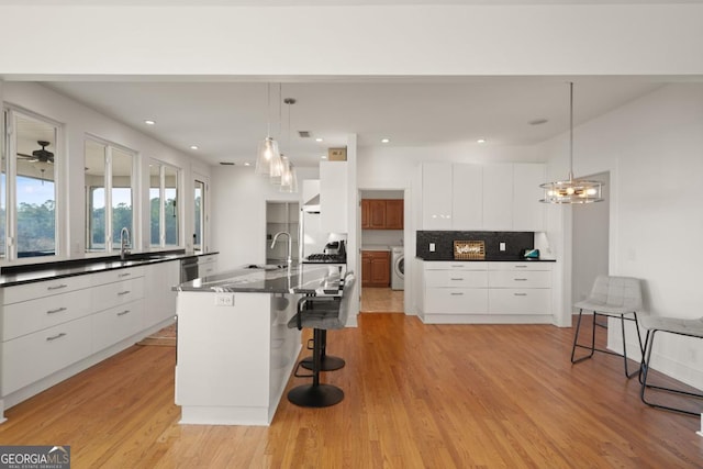 kitchen featuring a breakfast bar, a spacious island, white cabinetry, and washer / dryer