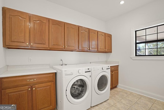 clothes washing area featuring washing machine and dryer, light tile patterned floors, and cabinets