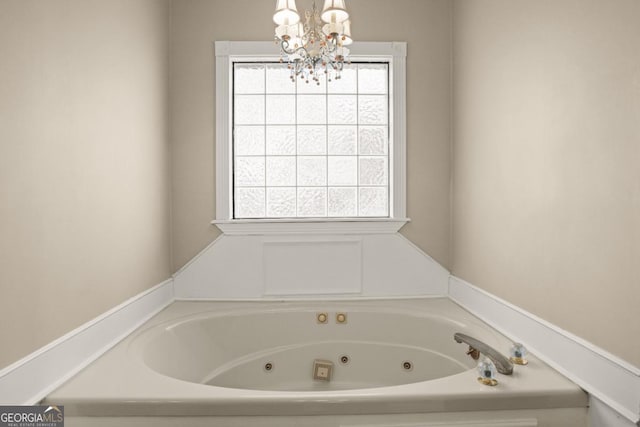 bathroom with a washtub, a chandelier, and plenty of natural light