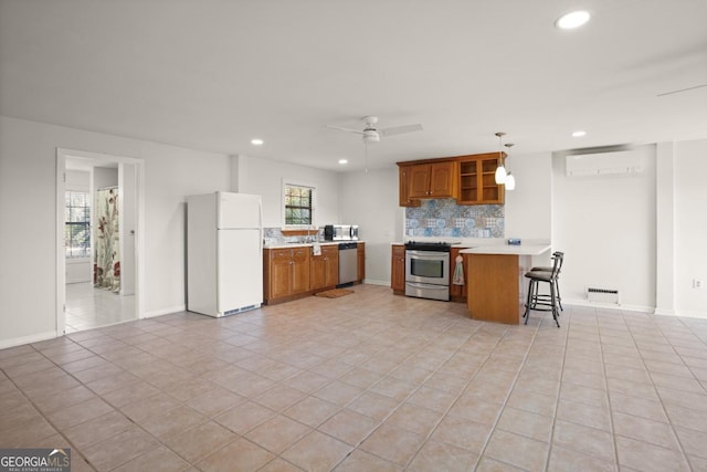 kitchen with hanging light fixtures, appliances with stainless steel finishes, a wall mounted AC, kitchen peninsula, and a breakfast bar area