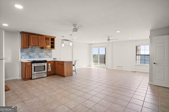 kitchen featuring decorative light fixtures, stainless steel stove, light tile patterned floors, and tasteful backsplash