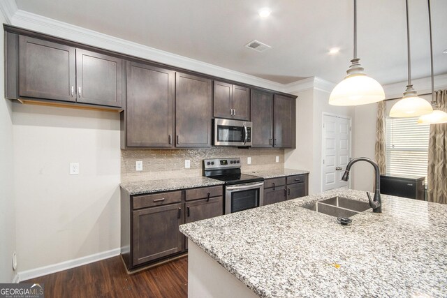 kitchen with appliances with stainless steel finishes, hanging light fixtures, crown molding, light stone countertops, and sink