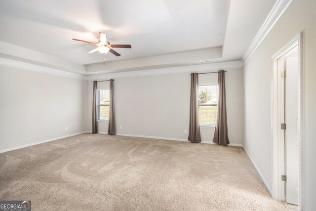 unfurnished room with ceiling fan, a raised ceiling, light carpet, and a healthy amount of sunlight