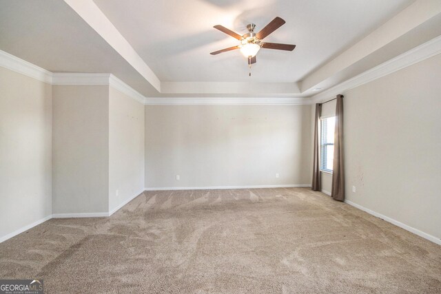 unfurnished room featuring light colored carpet, ceiling fan, a tray ceiling, and crown molding