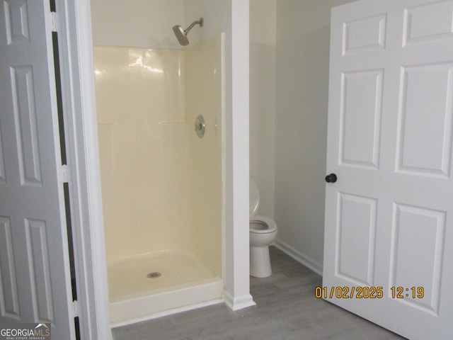 bathroom with a shower, hardwood / wood-style floors, and toilet