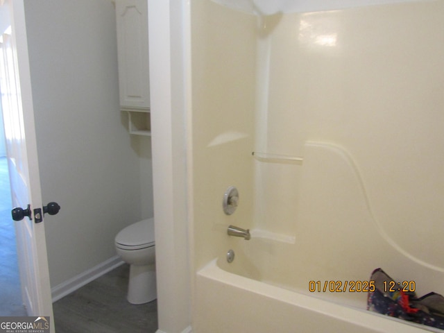 bathroom with hardwood / wood-style floors, toilet, and shower / tub combination