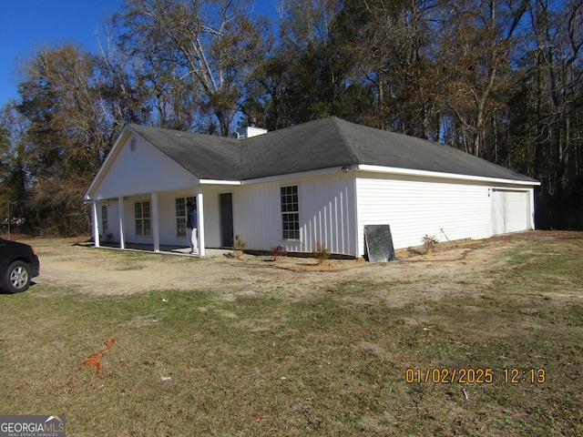 view of property exterior featuring a yard, covered porch, and a garage