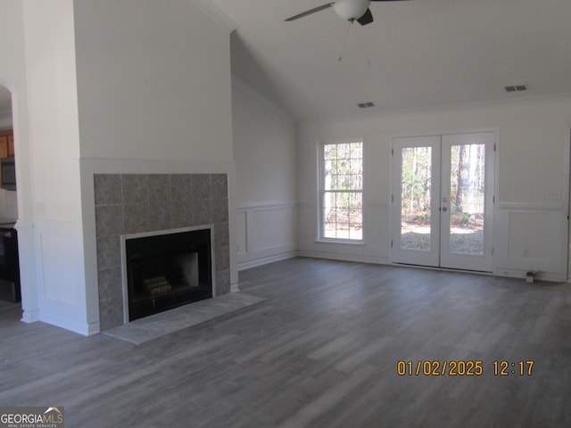 unfurnished living room with a tile fireplace, ceiling fan, french doors, and hardwood / wood-style flooring