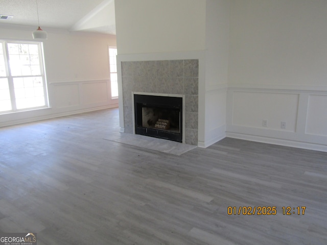 unfurnished living room featuring a textured ceiling, wood-type flooring, a fireplace, and vaulted ceiling