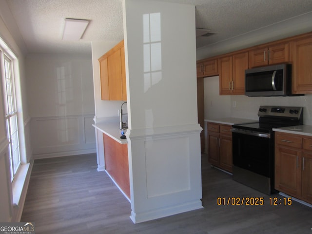 kitchen featuring a textured ceiling, stainless steel appliances, and dark wood-type flooring