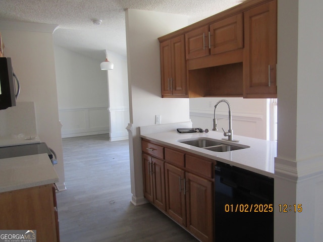 kitchen featuring a textured ceiling, sink, wood-type flooring, and black dishwasher