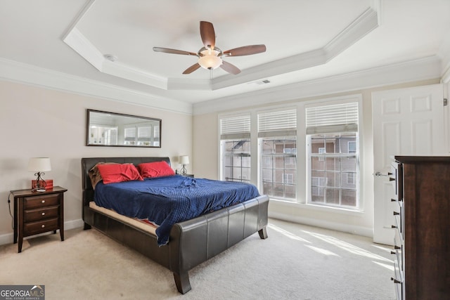 carpeted bedroom with a raised ceiling, ceiling fan, and ornamental molding