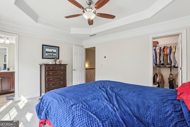 carpeted bedroom featuring ensuite bath, a raised ceiling, ceiling fan, a spacious closet, and a closet