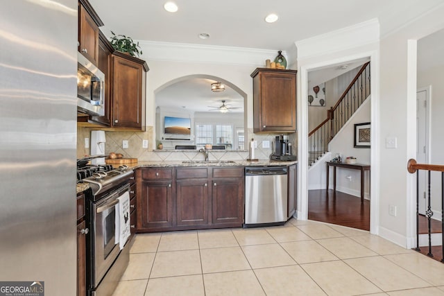 kitchen featuring sink, crown molding, ceiling fan, light stone counters, and stainless steel appliances