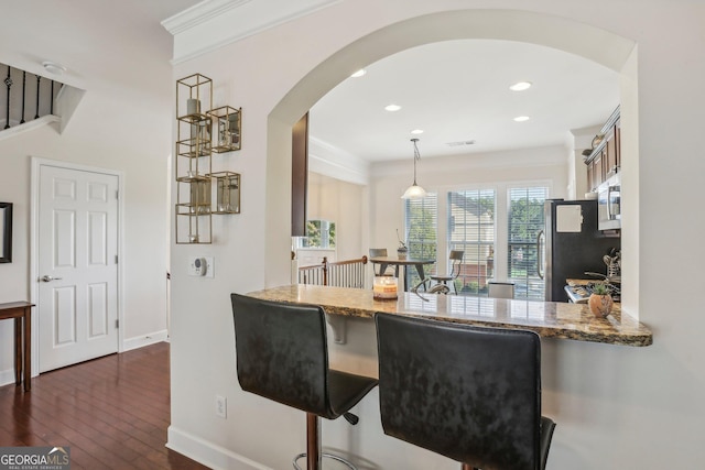 kitchen featuring dark hardwood / wood-style floors, kitchen peninsula, stainless steel fridge, pendant lighting, and stone countertops