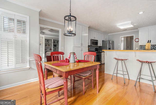 dining area featuring a textured ceiling, light hardwood / wood-style floors, an inviting chandelier, and crown molding