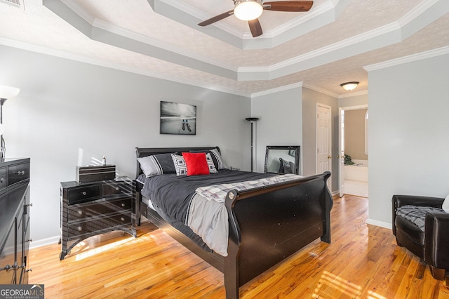 bedroom with a raised ceiling, ensuite bath, ceiling fan, and ornamental molding