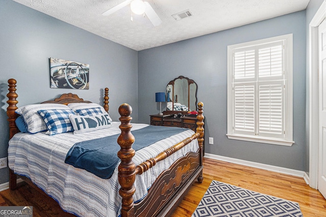 bedroom with a textured ceiling, hardwood / wood-style flooring, and ceiling fan