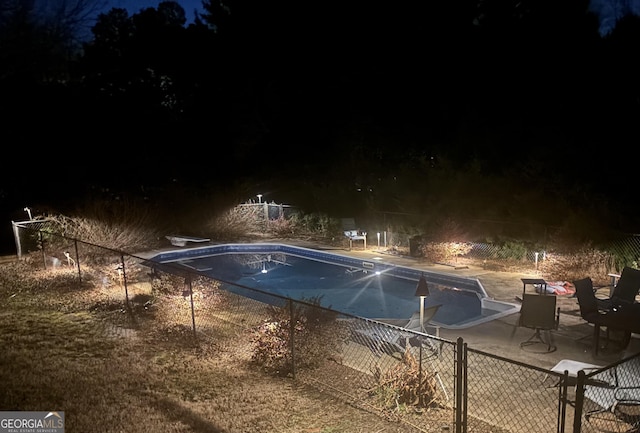 pool at twilight with a diving board and a patio