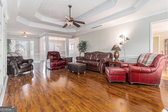 living room with dark wood-type flooring, a raised ceiling, crown molding, ceiling fan, and a textured ceiling