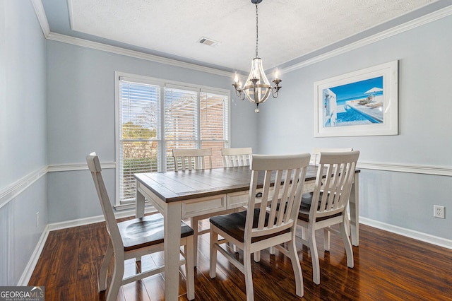 dining space with a textured ceiling, dark hardwood / wood-style flooring, an inviting chandelier, and crown molding