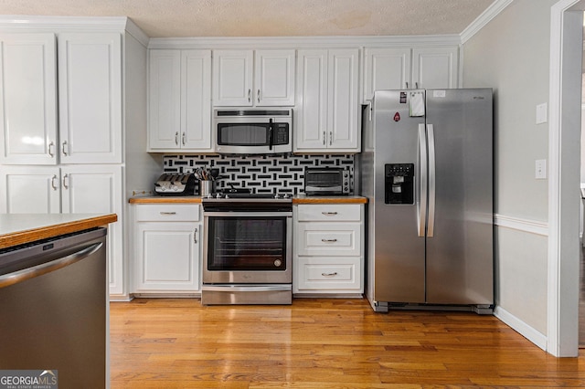 kitchen with decorative backsplash, appliances with stainless steel finishes, a textured ceiling, crown molding, and white cabinets