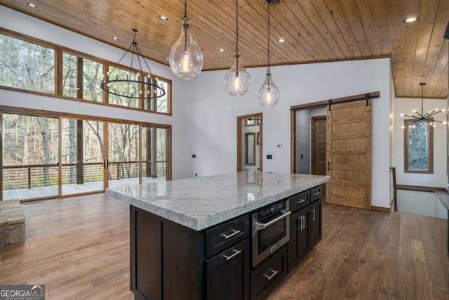 kitchen with wood ceiling, hanging light fixtures, a notable chandelier, a kitchen island, and a barn door