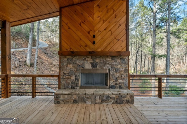 wooden terrace with an outdoor stone fireplace