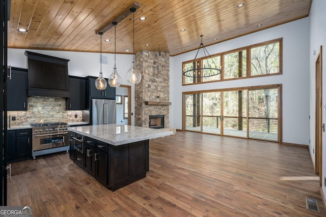 kitchen featuring hanging light fixtures, premium appliances, light stone countertops, a kitchen island, and wooden ceiling