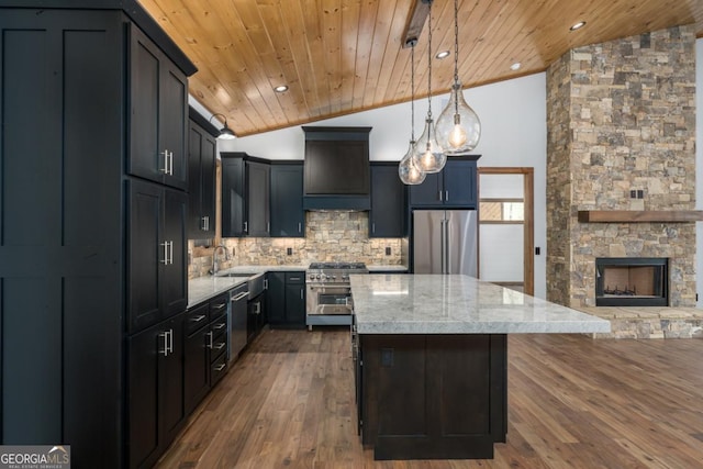 kitchen featuring pendant lighting, sink, light stone counters, premium appliances, and vaulted ceiling