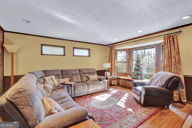 living room featuring wooden walls, a textured ceiling, hardwood / wood-style flooring, and crown molding