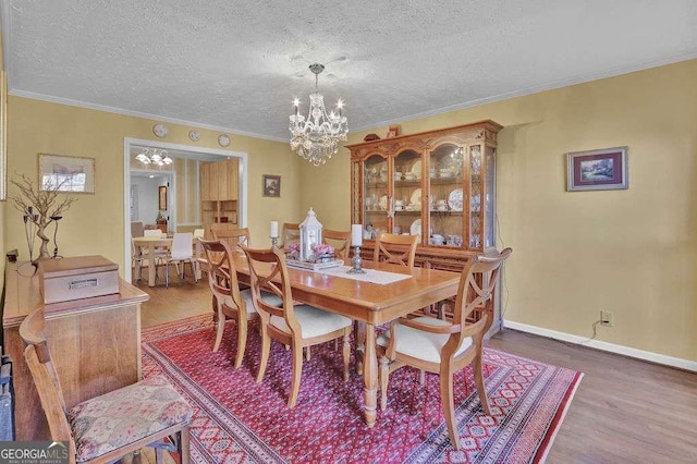 dining area featuring hardwood / wood-style floors, crown molding, a textured ceiling, and a chandelier