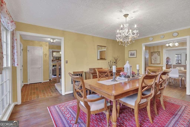 dining space featuring crown molding, wood-type flooring, a textured ceiling, and an inviting chandelier