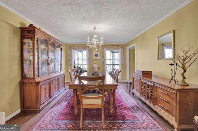 dining room featuring crown molding, hardwood / wood-style floors, a textured ceiling, and a notable chandelier