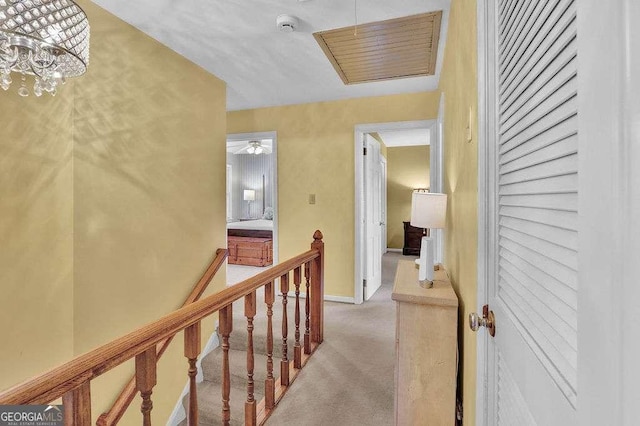 hall featuring light colored carpet and a chandelier