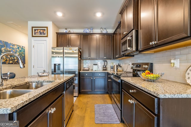 kitchen featuring sink, light hardwood / wood-style flooring, decorative backsplash, light stone countertops, and stainless steel appliances