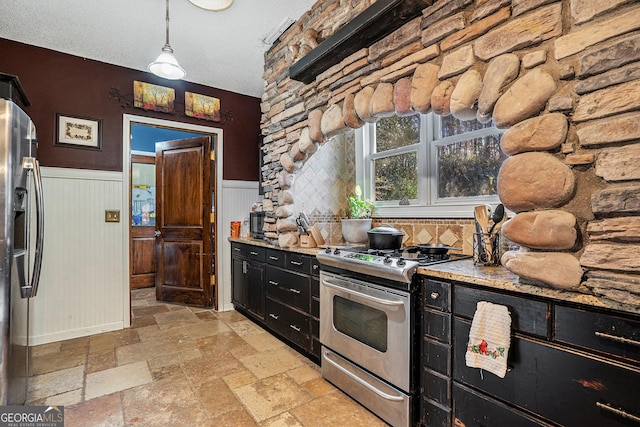 kitchen featuring stainless steel appliances, hanging light fixtures, a textured ceiling, and light stone counters