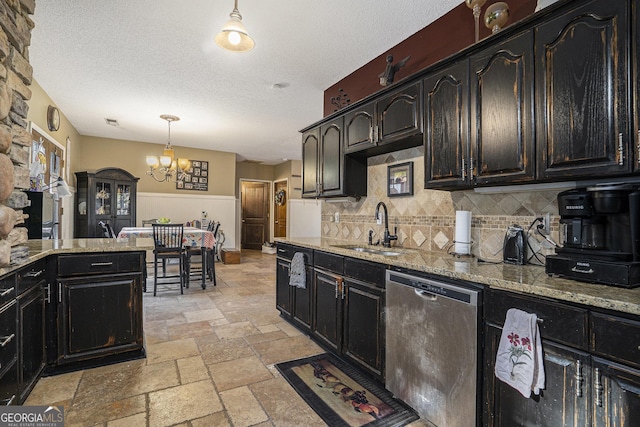 kitchen with stainless steel dishwasher, sink, pendant lighting, backsplash, and light stone counters