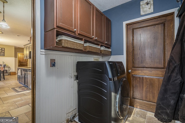 laundry room with washing machine and clothes dryer, wood walls, a textured ceiling, and cabinets