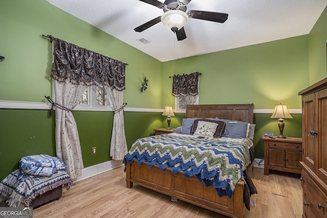 bedroom with a textured ceiling, light hardwood / wood-style flooring, and ceiling fan