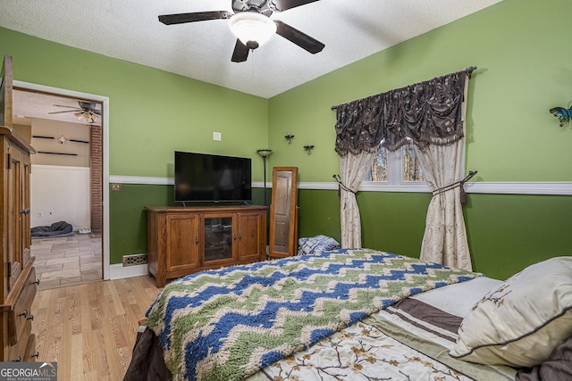 bedroom featuring ceiling fan, light hardwood / wood-style floors, and a textured ceiling