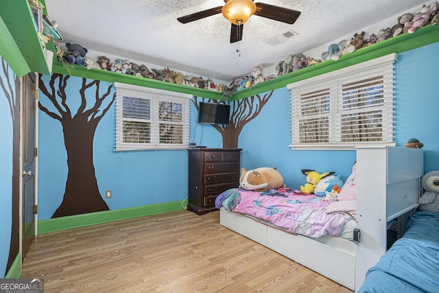 bedroom with ceiling fan, a textured ceiling, and hardwood / wood-style flooring