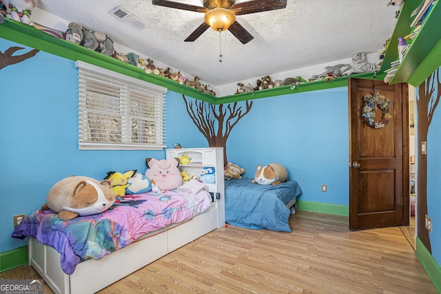 bedroom featuring light wood-type flooring, a textured ceiling, and ceiling fan