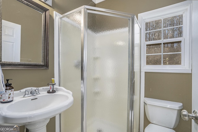 bathroom with sink, toilet, and an enclosed shower