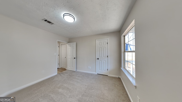 carpeted spare room featuring a wealth of natural light and a textured ceiling