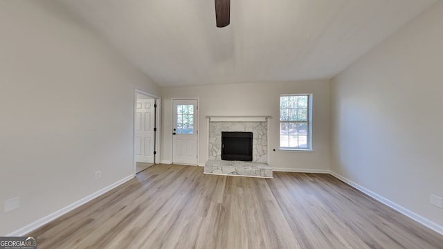 unfurnished living room featuring a fireplace, light hardwood / wood-style floors, ceiling fan, and lofted ceiling