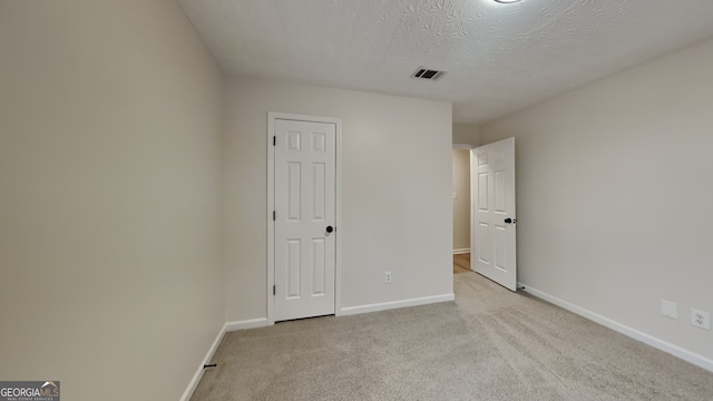 empty room featuring a textured ceiling and light carpet