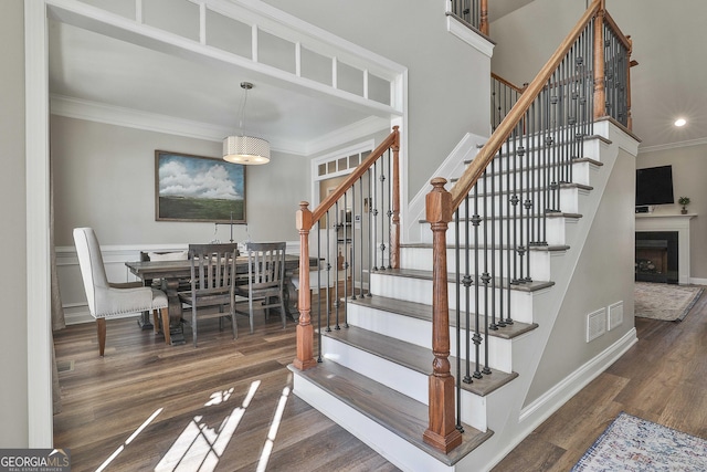 stairway with ornamental molding and hardwood / wood-style floors