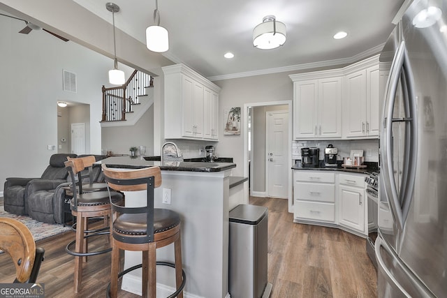 kitchen featuring pendant lighting, appliances with stainless steel finishes, white cabinetry, tasteful backsplash, and dark hardwood / wood-style floors